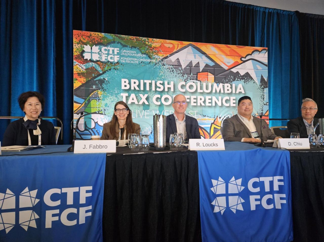 Ray Loucks seated on the speakers' panel at the Canadian Tax Foundation's 2026 British Columbia Tax Conference, between co-author Jessica Fabbro and fellow speaker Davis Chiu, with the conference backdrop behind them